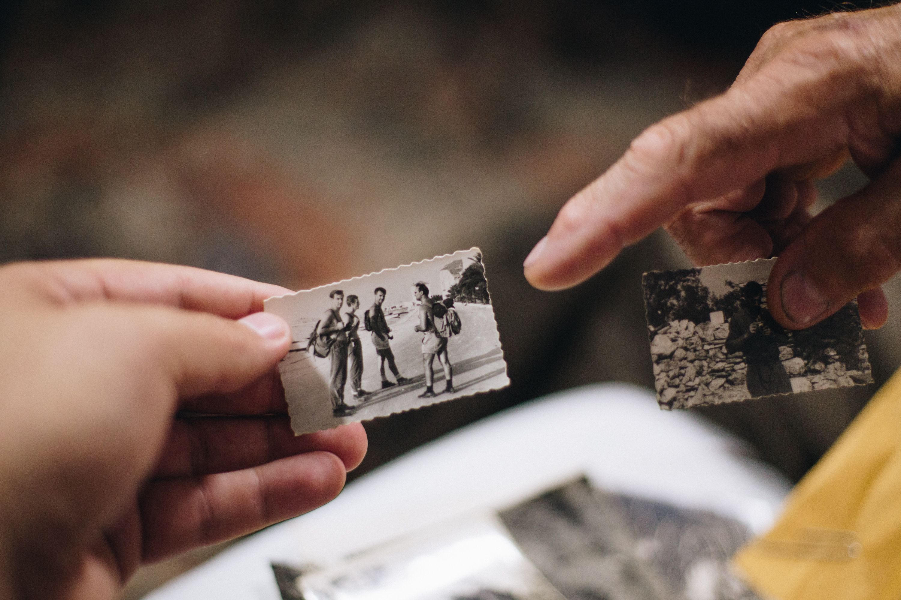 Two hands passing old black-and-white family photos